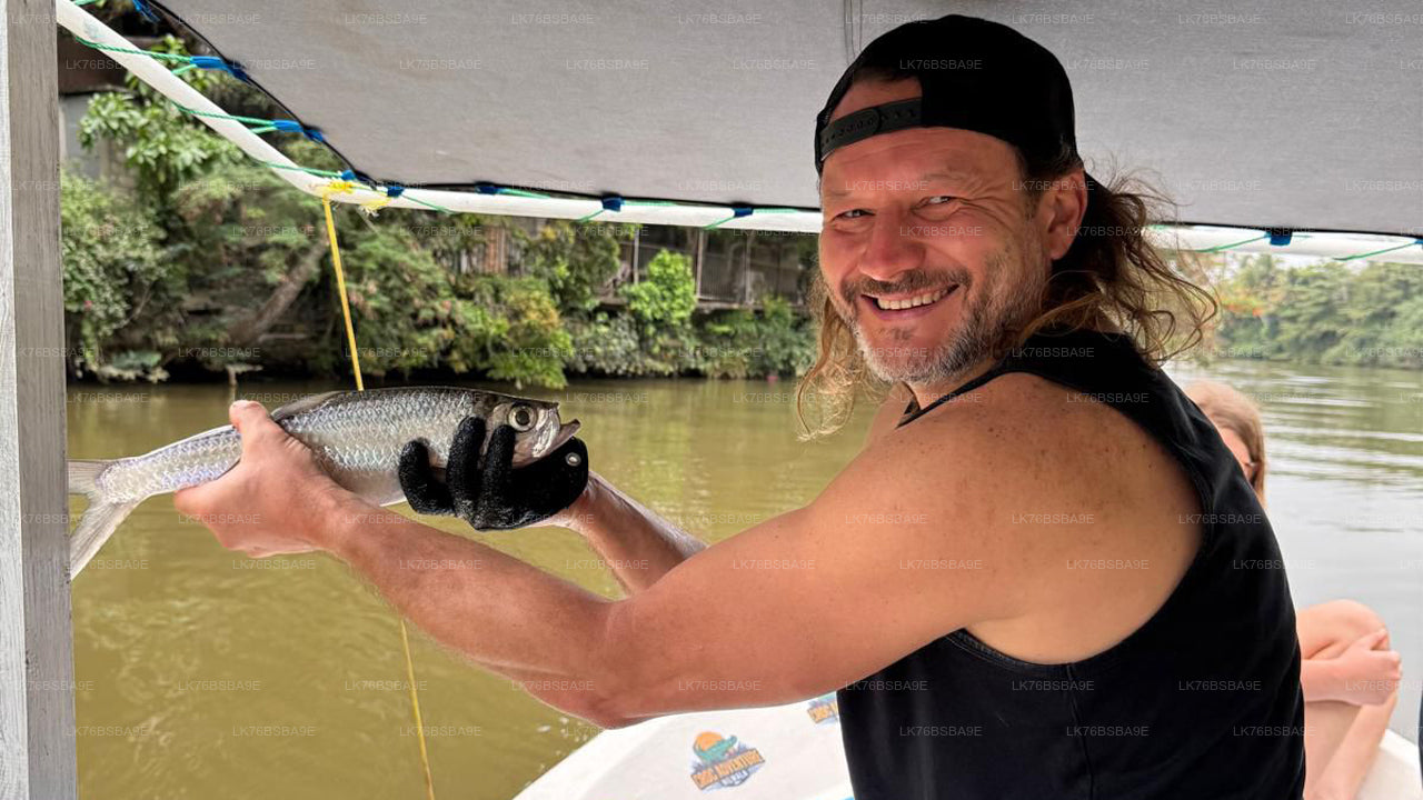 Man holding a fish on a boat with a river and trees in the background