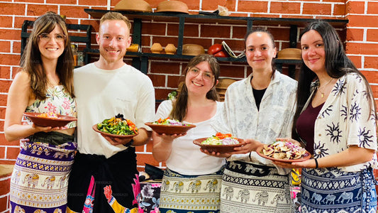 Five people holding plates of food in front of a brick wall.