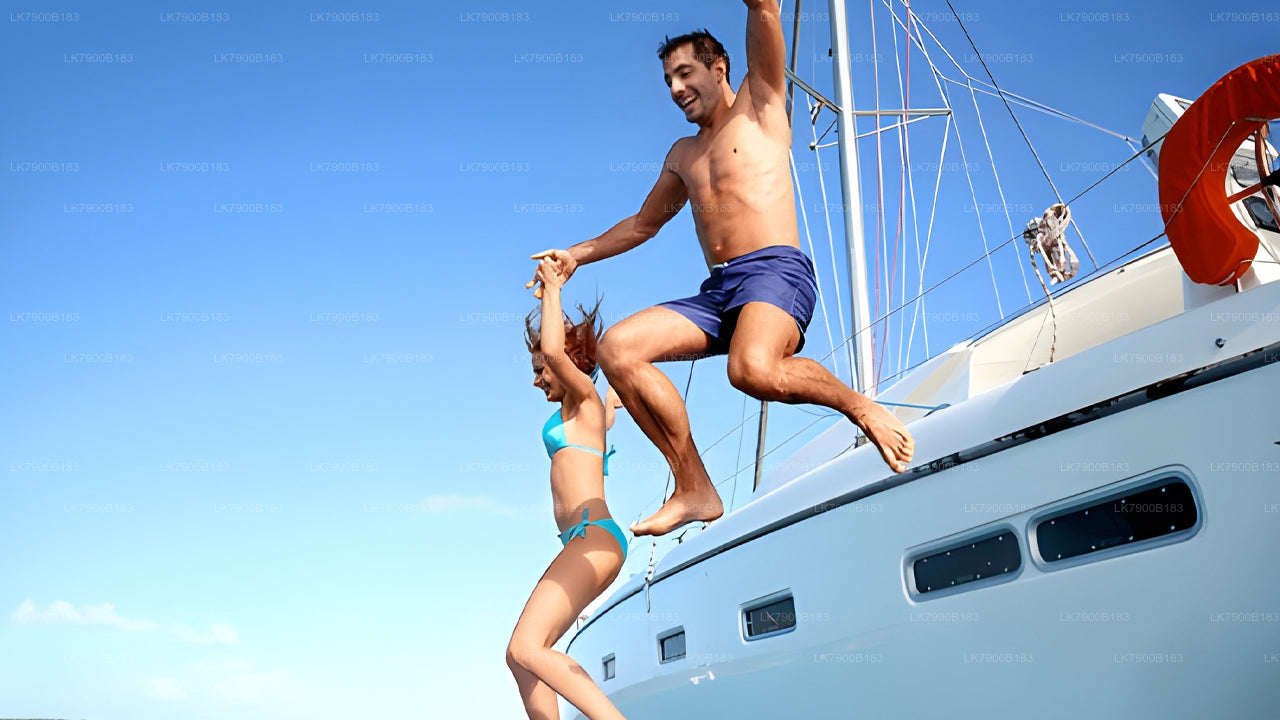 Two people jumping off a sailboat into the water on a clear day.